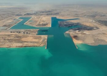 في إطار تنفيذ توجيهات فخامة الرئيس عبد الفتاح السيسي، رئيس الجمهورية، بالمضي قدمًا في خطة تطوير ورفع كفاءة الموانئ المصرية وتحويلها إلى مراكز إقليمية للنقل واللوجستيات وتجارة الترانزيت، يتواصل العمل بوتيرة متسارعة في مشروع تطوير ميناء السخنة، أحد أبرز الموانئ المصرية على البحر الأحمر. ويمثل ميناء السخنة أحد الركائز الأساسية لممر لوجستي عملاق يربط بين البحرين الأحمر والمتوسط عبر محور "السخنة – الإسكندرية"، في إطار المخطط المتكامل لتطوير موانئ الجمهورية وتعزيز قدراتها التنافسية على خريطة التجارة الإقليمية والدولية. وقد شهد المشروع إنجازًا هامًا بتسجيل نسبة تنفيذ 100% في أعمال البنية التحتية لمحطة حاويات "هاتشيسون"، أولى المحطات ضمن خطة تطوير الميناء، مع تواصل العمل في تنفيذ أعمال البنية الفوقية التي تشمل إنشاء الساحات، المباني الإدارية، والأسوار. ويمتد ميناء السخنة على مساحة 29 كيلومترًا مربعًا، ويتضمن المشروع إنشاء 5 أحواض جديدة و18 كيلومترًا من الأرصفة البحرية بعمق يصل إلى 18 مترًا، بالإضافة إلى ساحات تداول بمساحة 9.2 مليون متر مربع، ومناطق لوجستية بمساحة 5.2 كيلومتر مربع، إلى جانب شبكة طرق داخلية بطول 17 كيلومترًا من الرصف الخرساني، وشبكة سكك حديدية بطول 30 كيلومترًا متصلة بخط القطار الكهربائي السريع. ويُعد المشروع جزءًا من المخطط الشامل لتحويل ميناء السخنة إلى ميناء محوري متكامل، بما يسهم في مضاعفة حصة مصر من تجارة الترانزيت العالمية، وتعزيز تنافسية الموانئ المصرية كمراكز إقليمية وعالمية للخدمات اللوجستية. وفي هذا السياق، يأتي التعاون مع كبرى التحالفات العالمية في إدارة وتشغيل الخطوط الملاحية ومحطات الحاويات الدولية كخطوة استراتيجية ضمن خطة وزارة النقل لعقد شراكات مع أكبر الشركات المتخصصة عالميًا، بما يضمن جذب مزيد من الخطوط الملاحية وتكثيف حركة السفن بالموانئ المصرية، بما يواكب مستهدفات الدولة في تعزيز مكانتها كمركز إقليمي ودولي للتجارة البحرية والخدمات اللوجستية.