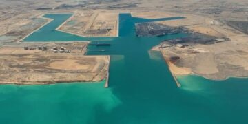 في إطار تنفيذ توجيهات فخامة الرئيس عبد الفتاح السيسي، رئيس الجمهورية، بالمضي قدمًا في خطة تطوير ورفع كفاءة الموانئ المصرية وتحويلها إلى مراكز إقليمية للنقل واللوجستيات وتجارة الترانزيت، يتواصل العمل بوتيرة متسارعة في مشروع تطوير ميناء السخنة، أحد أبرز الموانئ المصرية على البحر الأحمر. ويمثل ميناء السخنة أحد الركائز الأساسية لممر لوجستي عملاق يربط بين البحرين الأحمر والمتوسط عبر محور "السخنة – الإسكندرية"، في إطار المخطط المتكامل لتطوير موانئ الجمهورية وتعزيز قدراتها التنافسية على خريطة التجارة الإقليمية والدولية. وقد شهد المشروع إنجازًا هامًا بتسجيل نسبة تنفيذ 100% في أعمال البنية التحتية لمحطة حاويات "هاتشيسون"، أولى المحطات ضمن خطة تطوير الميناء، مع تواصل العمل في تنفيذ أعمال البنية الفوقية التي تشمل إنشاء الساحات، المباني الإدارية، والأسوار. ويمتد ميناء السخنة على مساحة 29 كيلومترًا مربعًا، ويتضمن المشروع إنشاء 5 أحواض جديدة و18 كيلومترًا من الأرصفة البحرية بعمق يصل إلى 18 مترًا، بالإضافة إلى ساحات تداول بمساحة 9.2 مليون متر مربع، ومناطق لوجستية بمساحة 5.2 كيلومتر مربع، إلى جانب شبكة طرق داخلية بطول 17 كيلومترًا من الرصف الخرساني، وشبكة سكك حديدية بطول 30 كيلومترًا متصلة بخط القطار الكهربائي السريع. ويُعد المشروع جزءًا من المخطط الشامل لتحويل ميناء السخنة إلى ميناء محوري متكامل، بما يسهم في مضاعفة حصة مصر من تجارة الترانزيت العالمية، وتعزيز تنافسية الموانئ المصرية كمراكز إقليمية وعالمية للخدمات اللوجستية. وفي هذا السياق، يأتي التعاون مع كبرى التحالفات العالمية في إدارة وتشغيل الخطوط الملاحية ومحطات الحاويات الدولية كخطوة استراتيجية ضمن خطة وزارة النقل لعقد شراكات مع أكبر الشركات المتخصصة عالميًا، بما يضمن جذب مزيد من الخطوط الملاحية وتكثيف حركة السفن بالموانئ المصرية، بما يواكب مستهدفات الدولة في تعزيز مكانتها كمركز إقليمي ودولي للتجارة البحرية والخدمات اللوجستية.